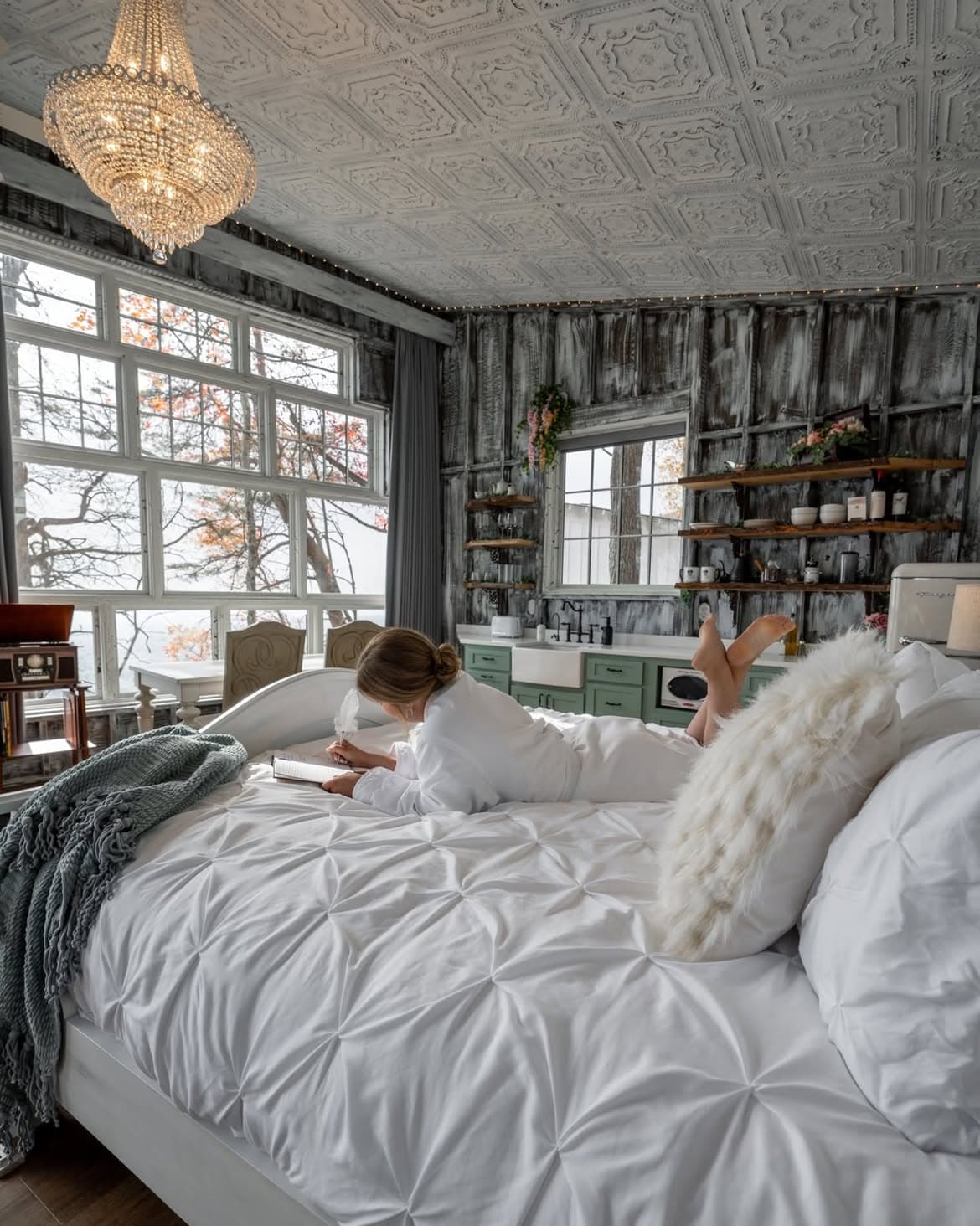 Guest journaling on a luxury bed inside a treehouse with chandelier at BOLT FARM Treehouse