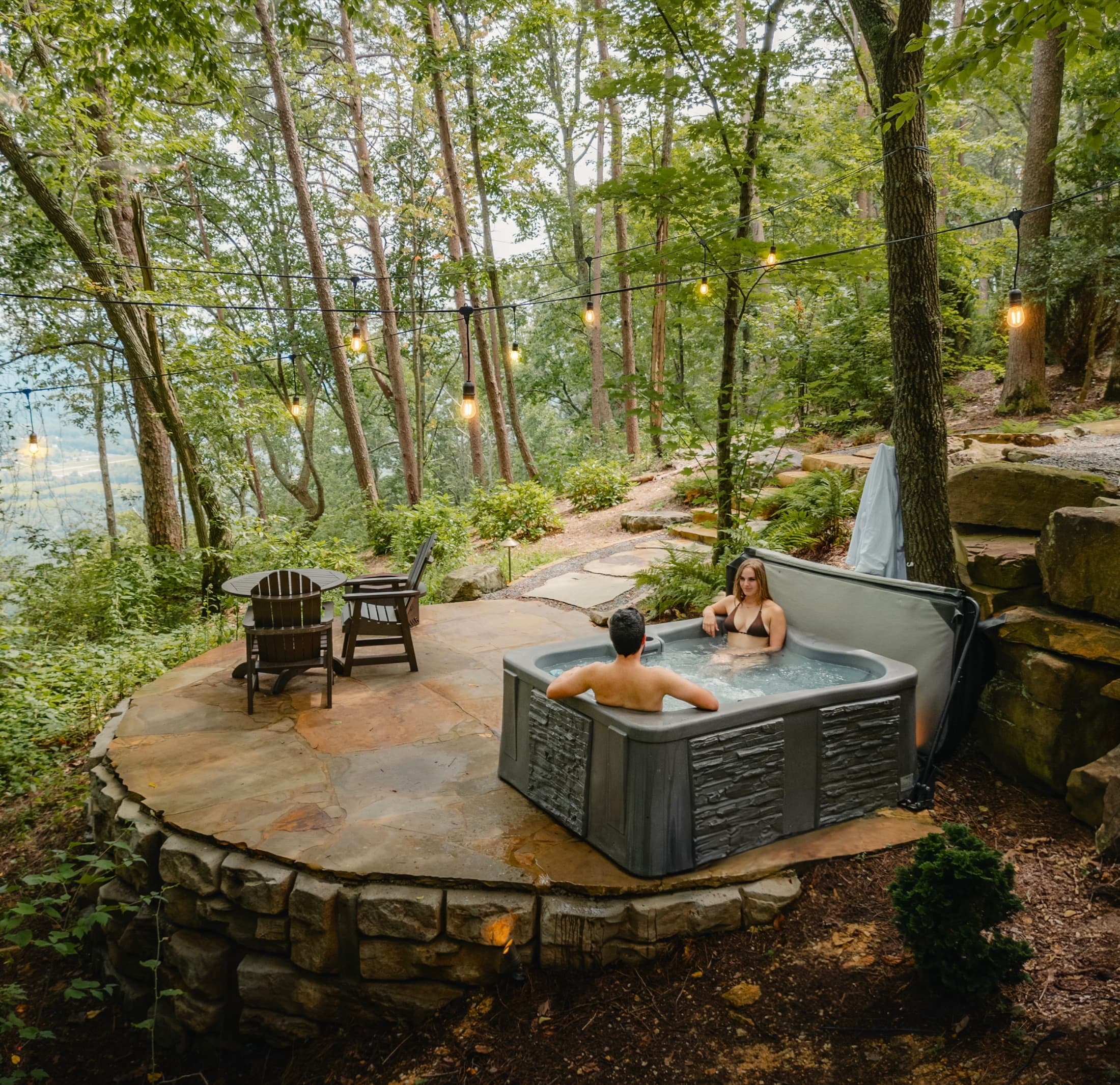A couple in a private hot tub overlooking the forest
